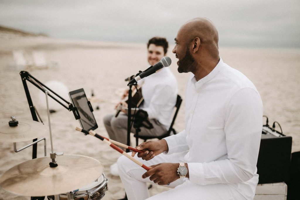 Heiraten mit Live Musik. Ein Get Together am Strand auf Sylt. Musiker spielen Schlagzeug und Gitarre.