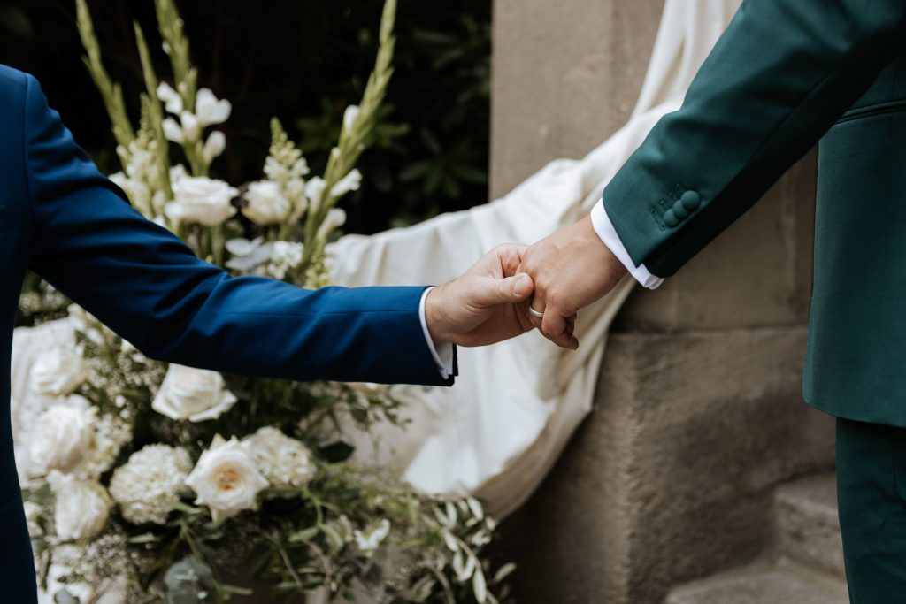 Zwei Männer halten Hand bei Hochzeit in Hamburg.