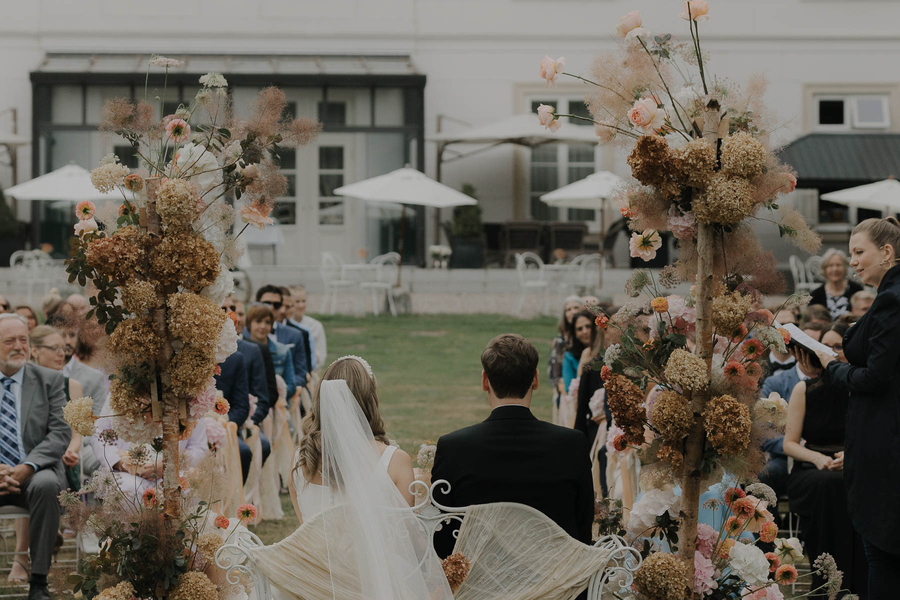 Hochzeitspaar sitzt bei der Trauung den Gästen zugewandt mit Blick auf Gut Bliestorf.